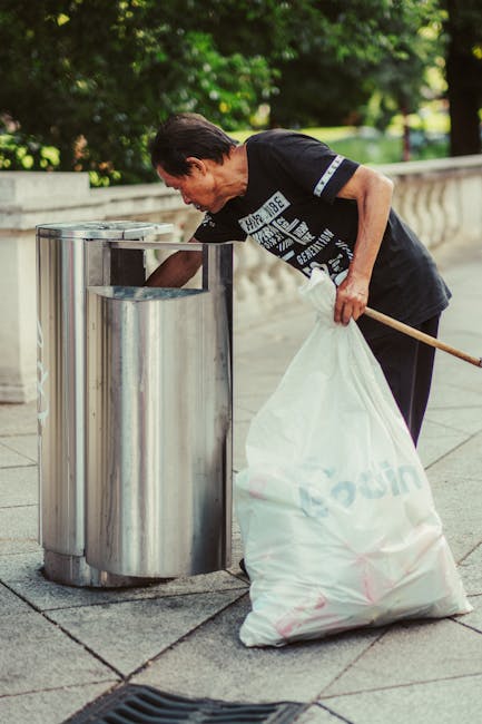 A large pile of black garbage bags filled with waste is stacked outdoors against a reflective, tiled wall with a graffiti marking in red spray paint that reads 'XEND'. The bags vary in size and are se